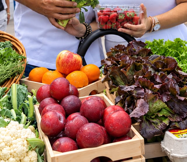 Couple standing behind table of produce