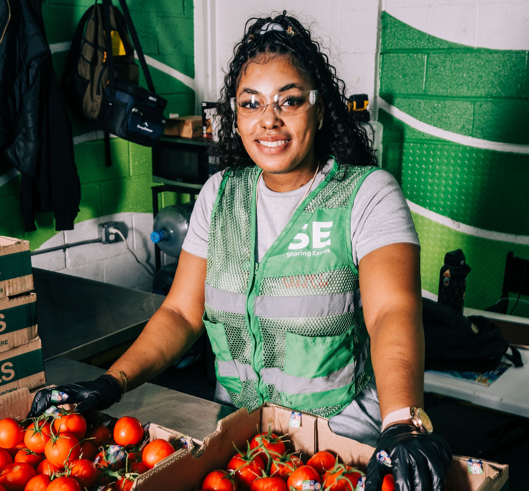 Woman standing in front of tomato boxes.