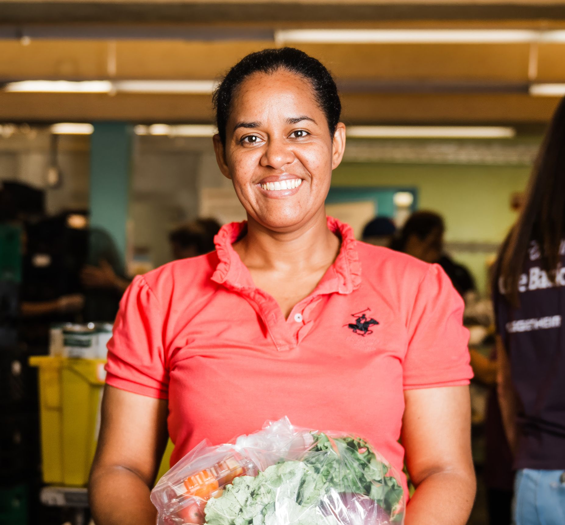Woman in orange shirt holding bag of food