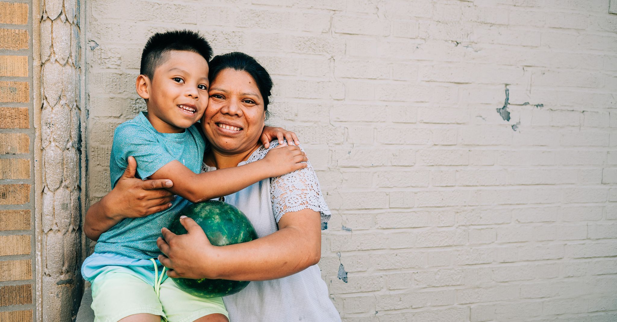 Woman and child in front of a white brick wall