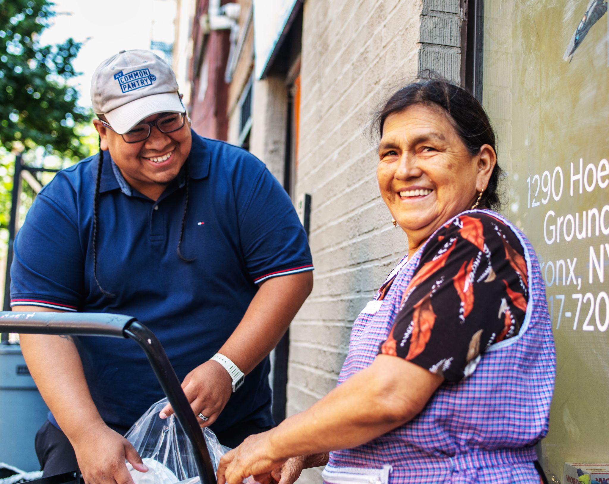 Man on street helping woman in purple apron